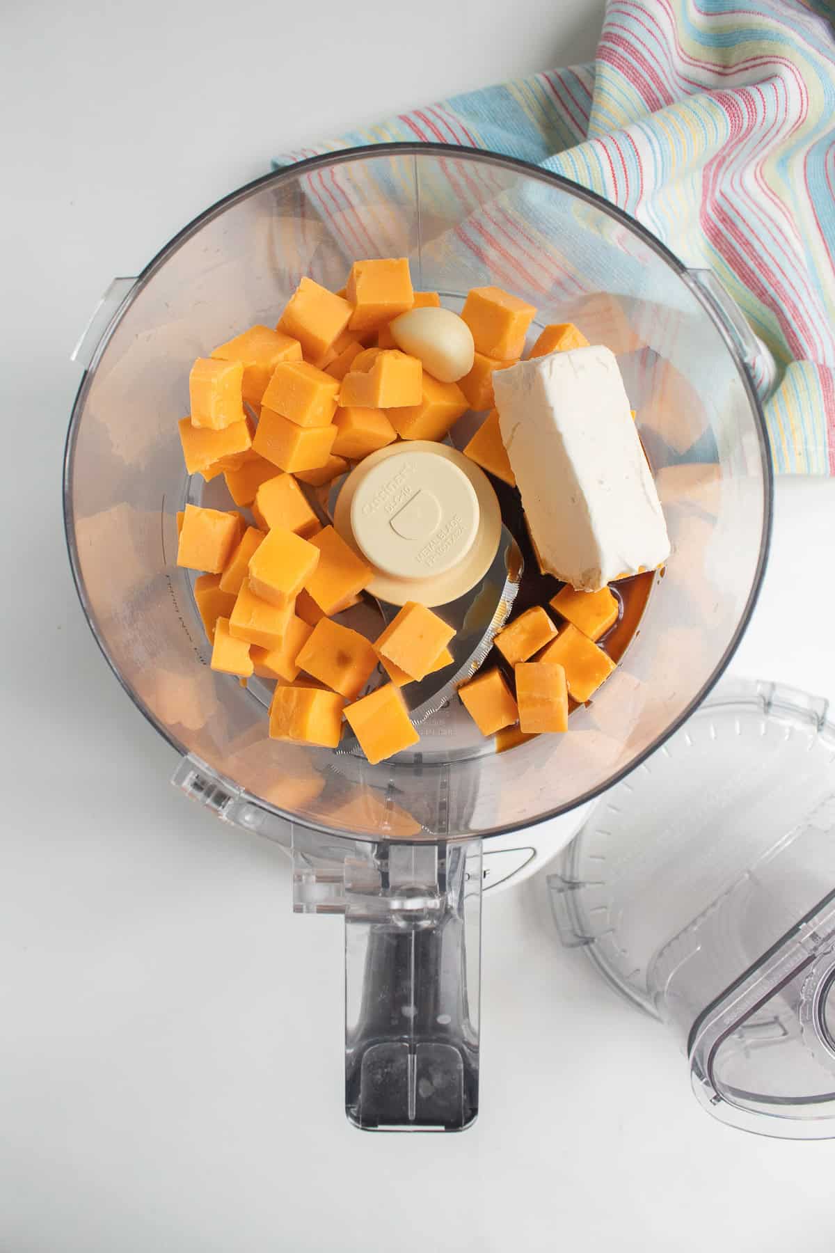 Cubed sharp cheddar, cream cheese, garlic, and Worcestershire sauce are added to a food processor.