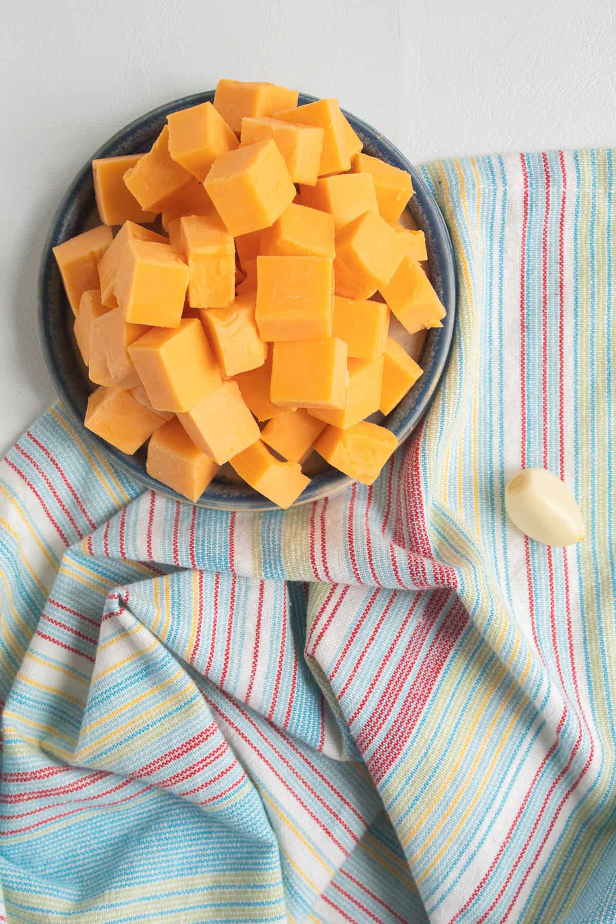 The sharp cheddar is cubed and the garlic clove is peeled and trimmed.