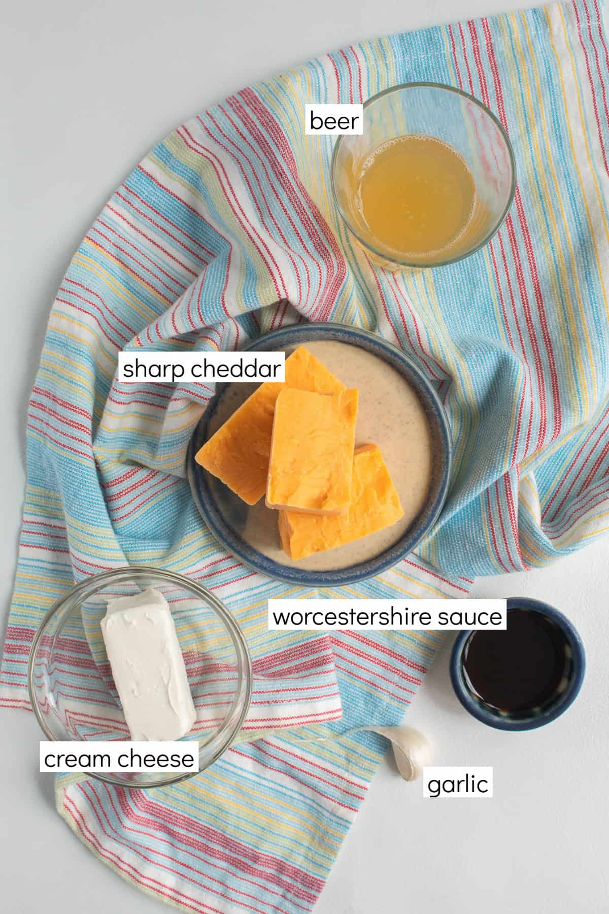 Ingredients for the recipe are displayed and labeled with white text boxes including the words beer, sharp cheddar, worcestershire sauce, cream cheese, and garlic.