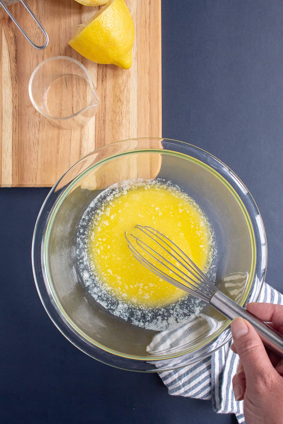 Butter is melted and whisked until smooth in a glass bowl.