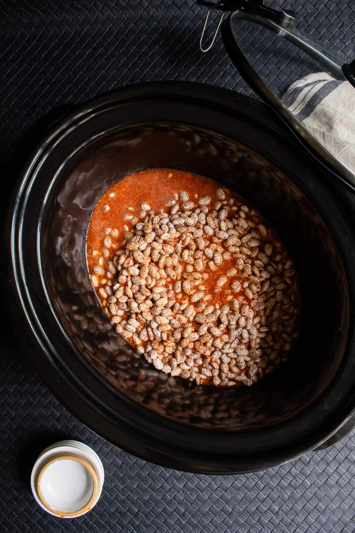 The dry pinto beans are covered with the seasoning liquid.