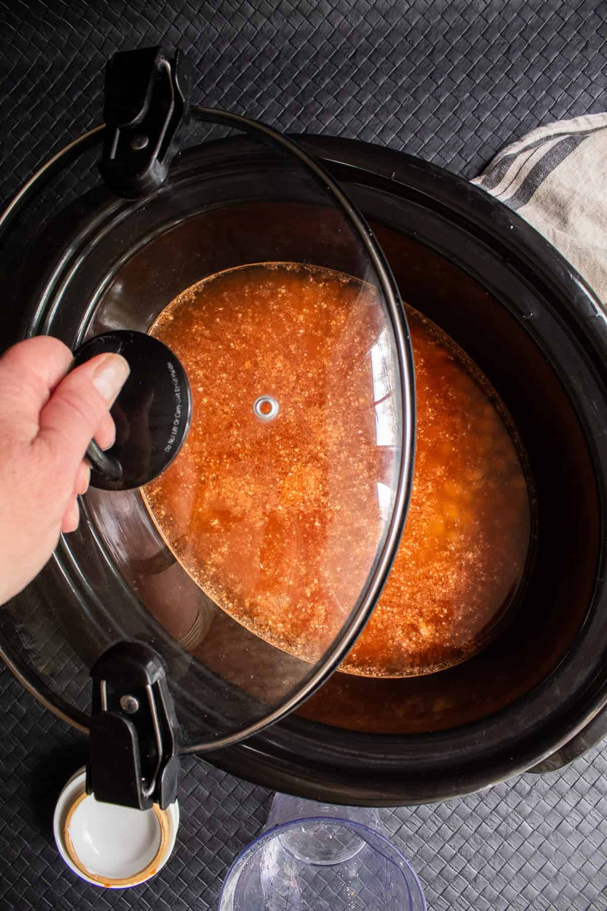The lid to the crock pot is place on top of the cooker after additional water is added.