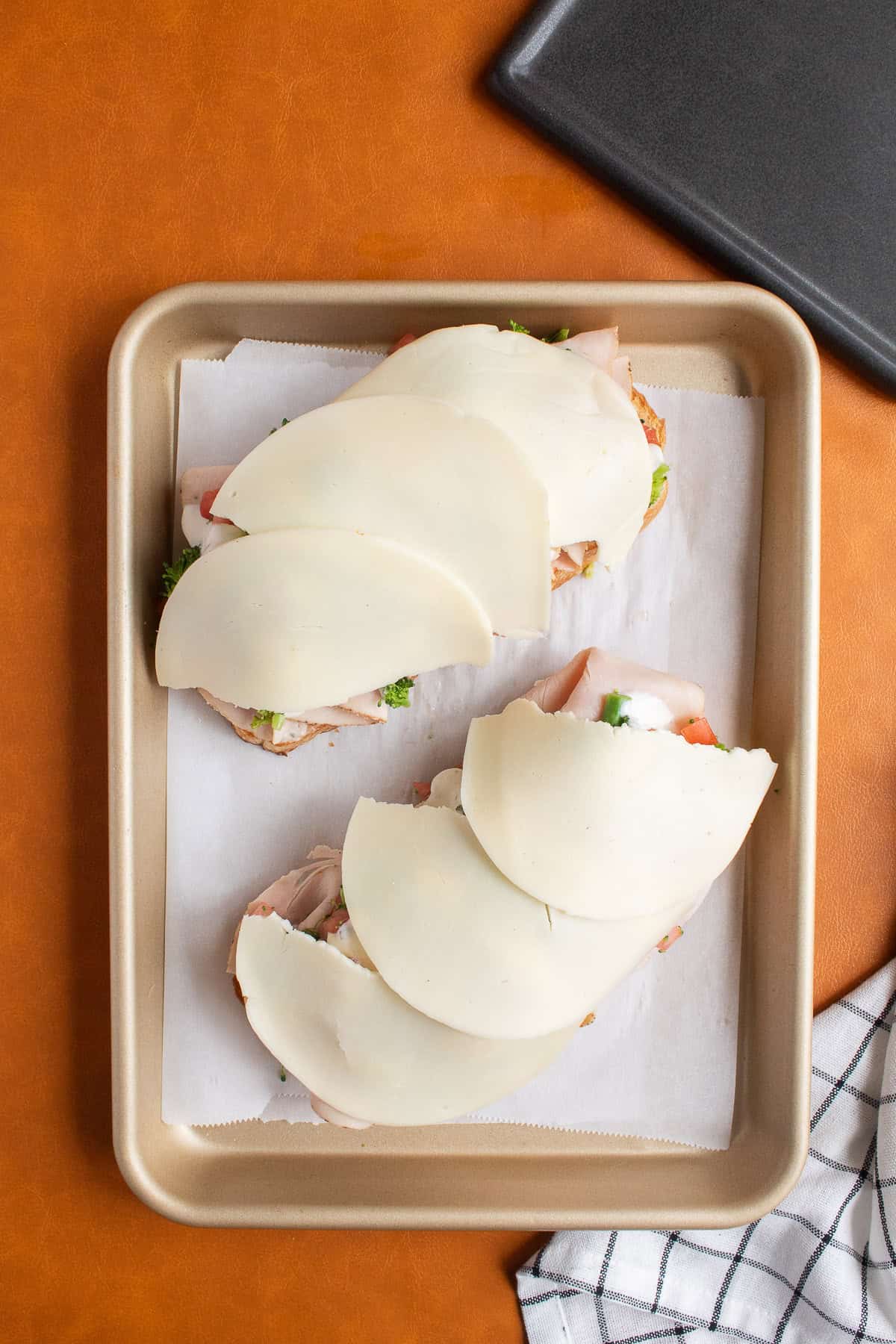 Sliced provolone is draped over the open faced sandwiches.