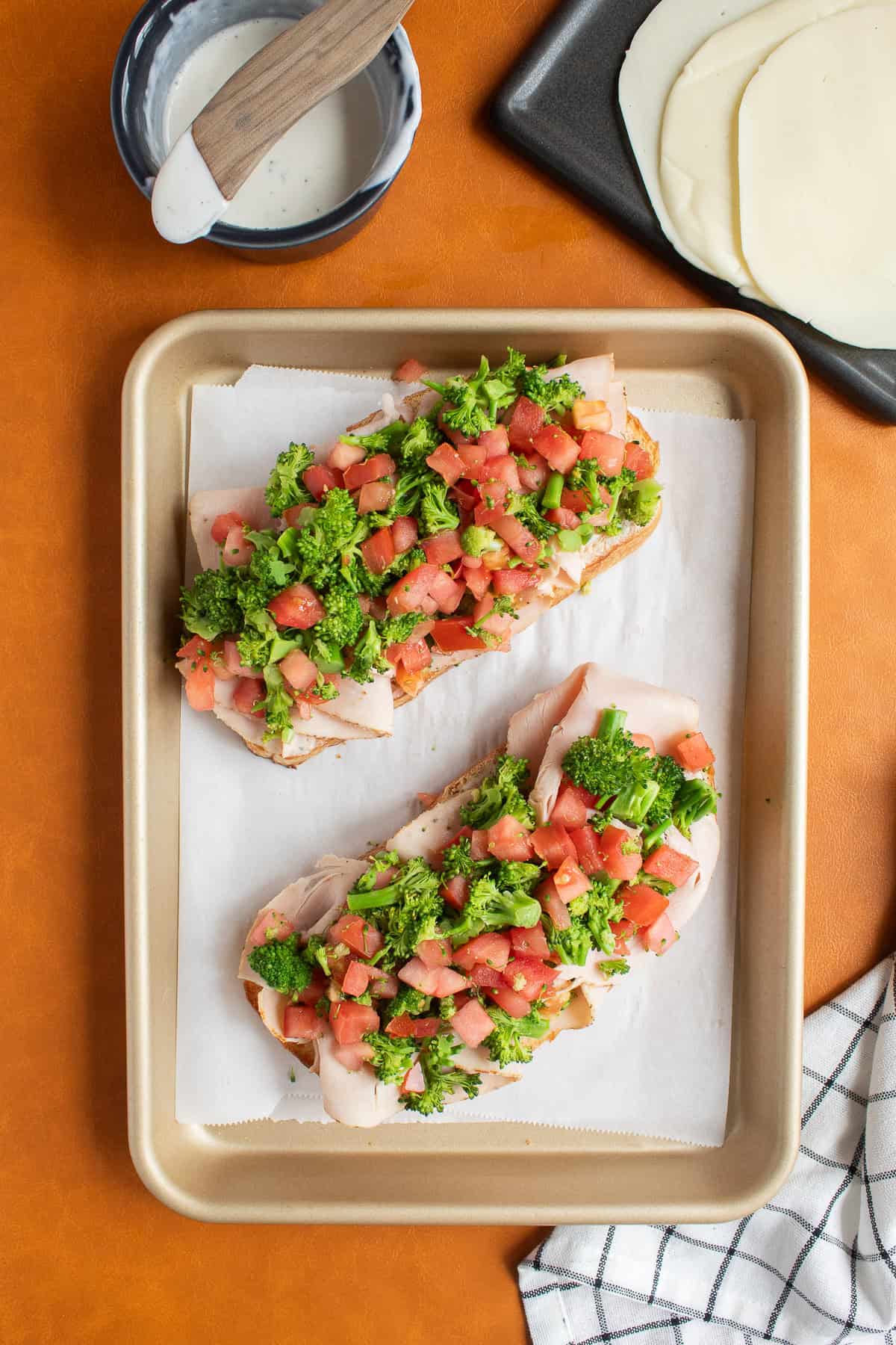 Broccoli and tomato are heaped on top of the sliced turkey.