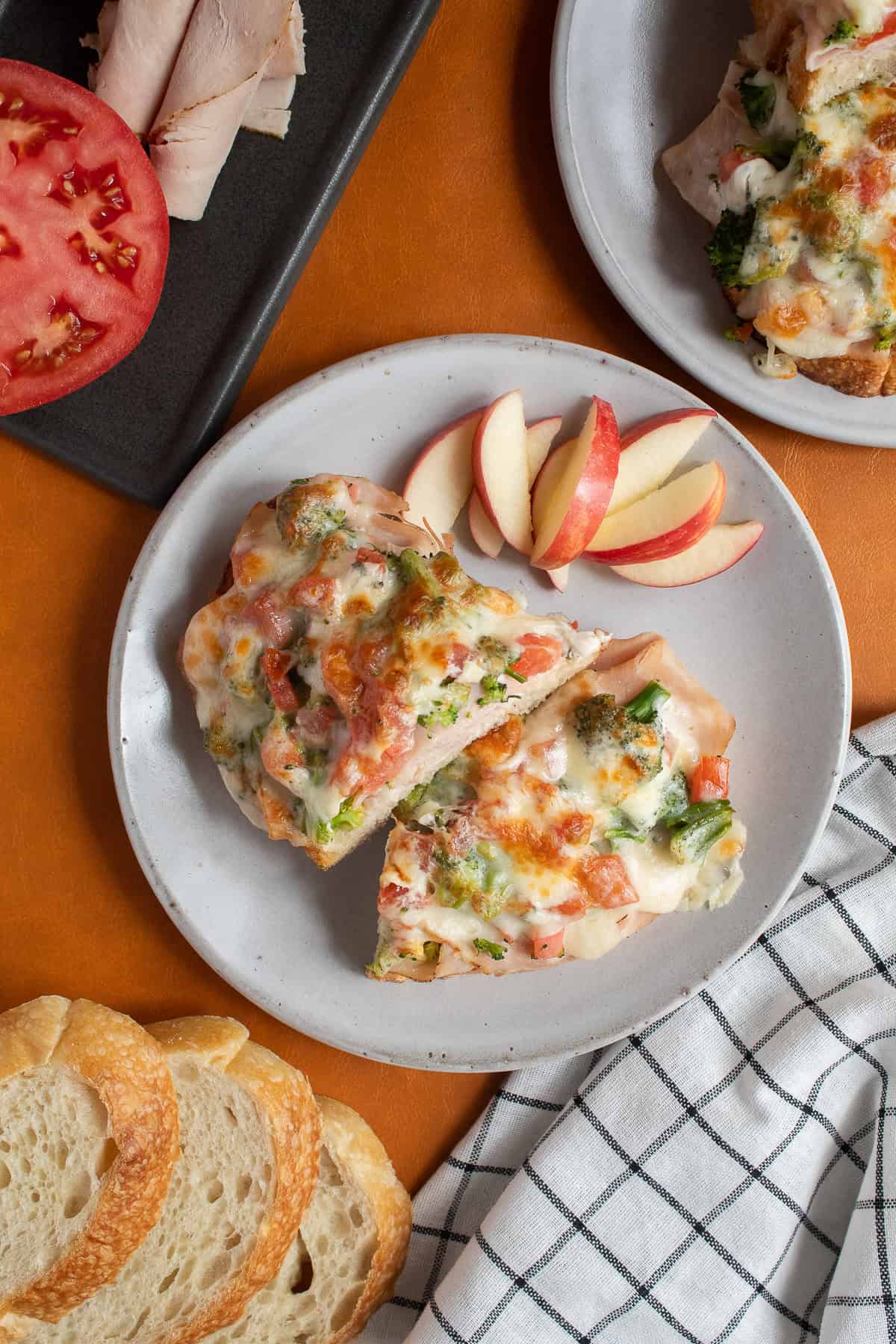 The broiled open faced turkey melt is served with apple slices.