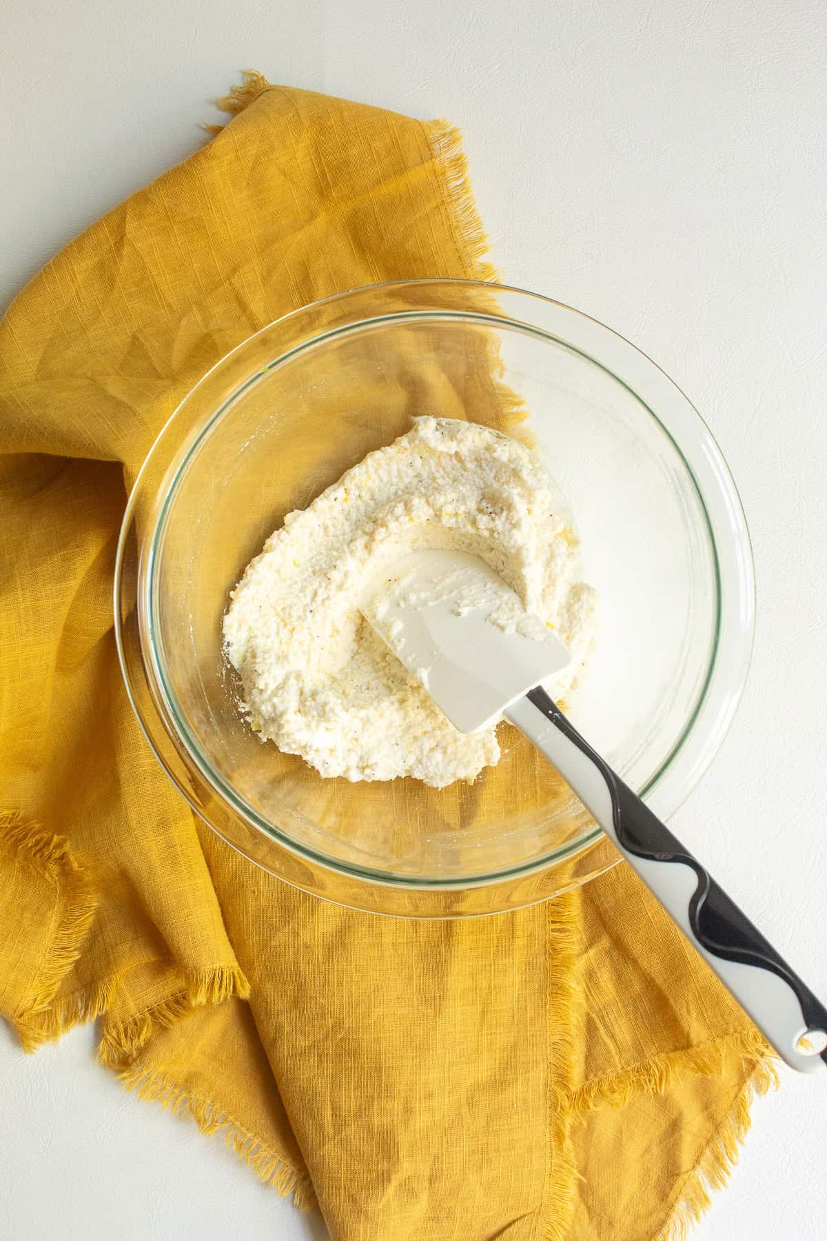 The ricotta is mixed with the lemon zest and Parmesan in a clear glass bowl.