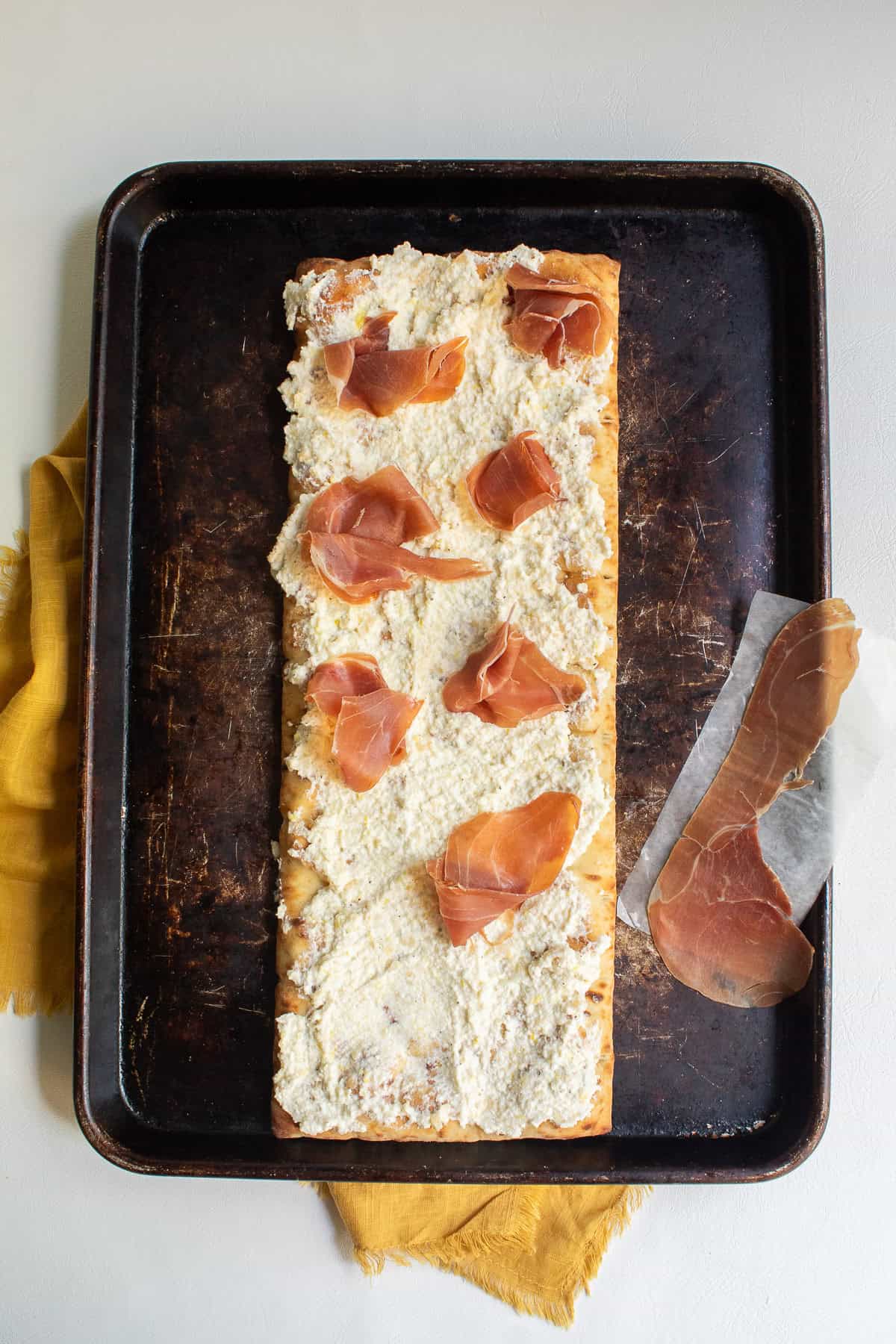 The prosciutto slices are torn into pieces and heaped on top pf the cheese in small bundles.