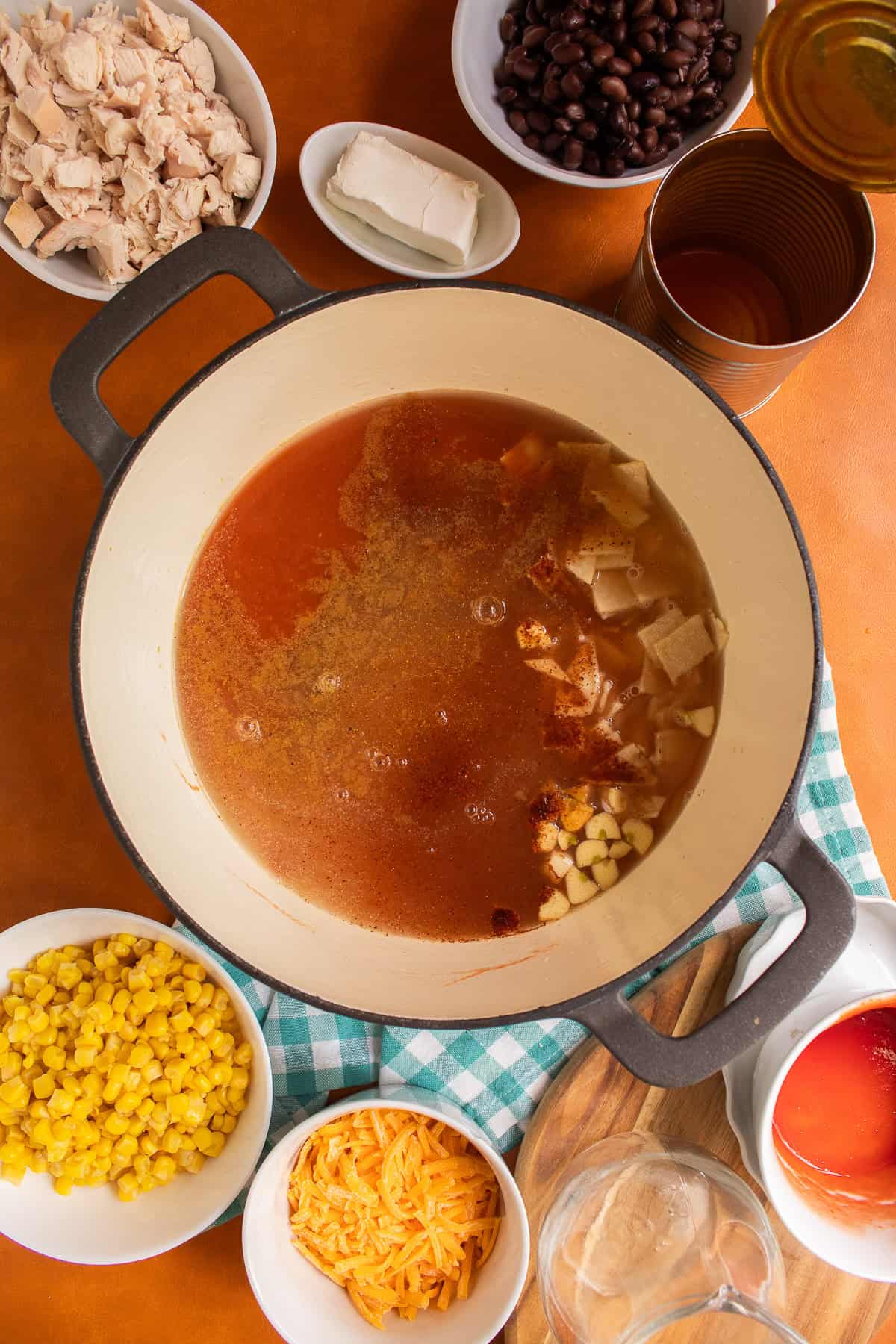 Broth, spices, and tortilla strips are added to a large soup pot.