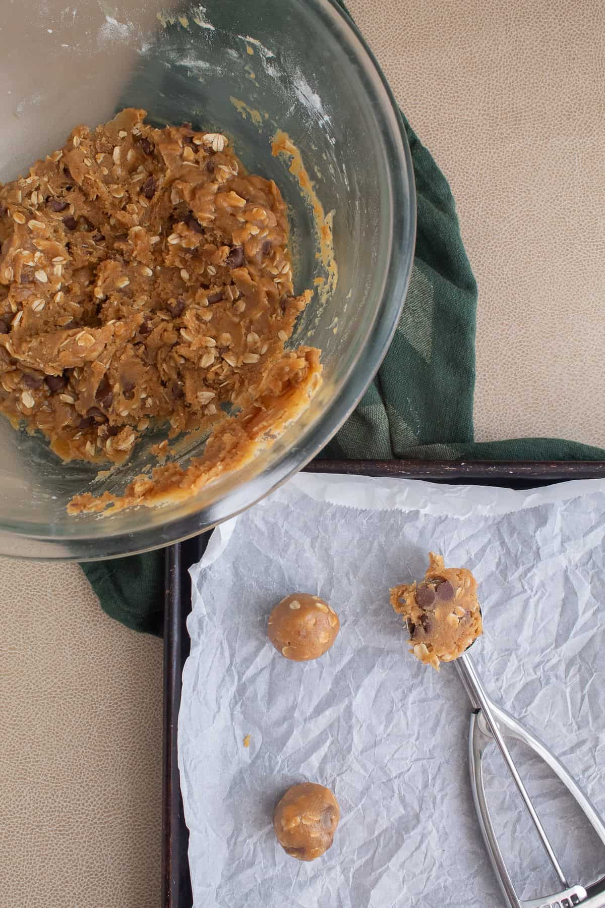 The chilled dough is portioned and rolled into balls before being placed in the cookie sheet.