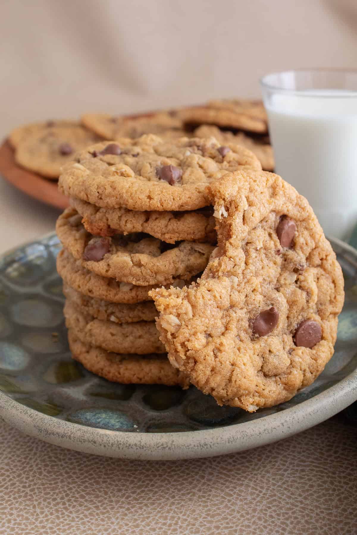A stack of cookies studded with chocolate chips sits on a green patterned plate.