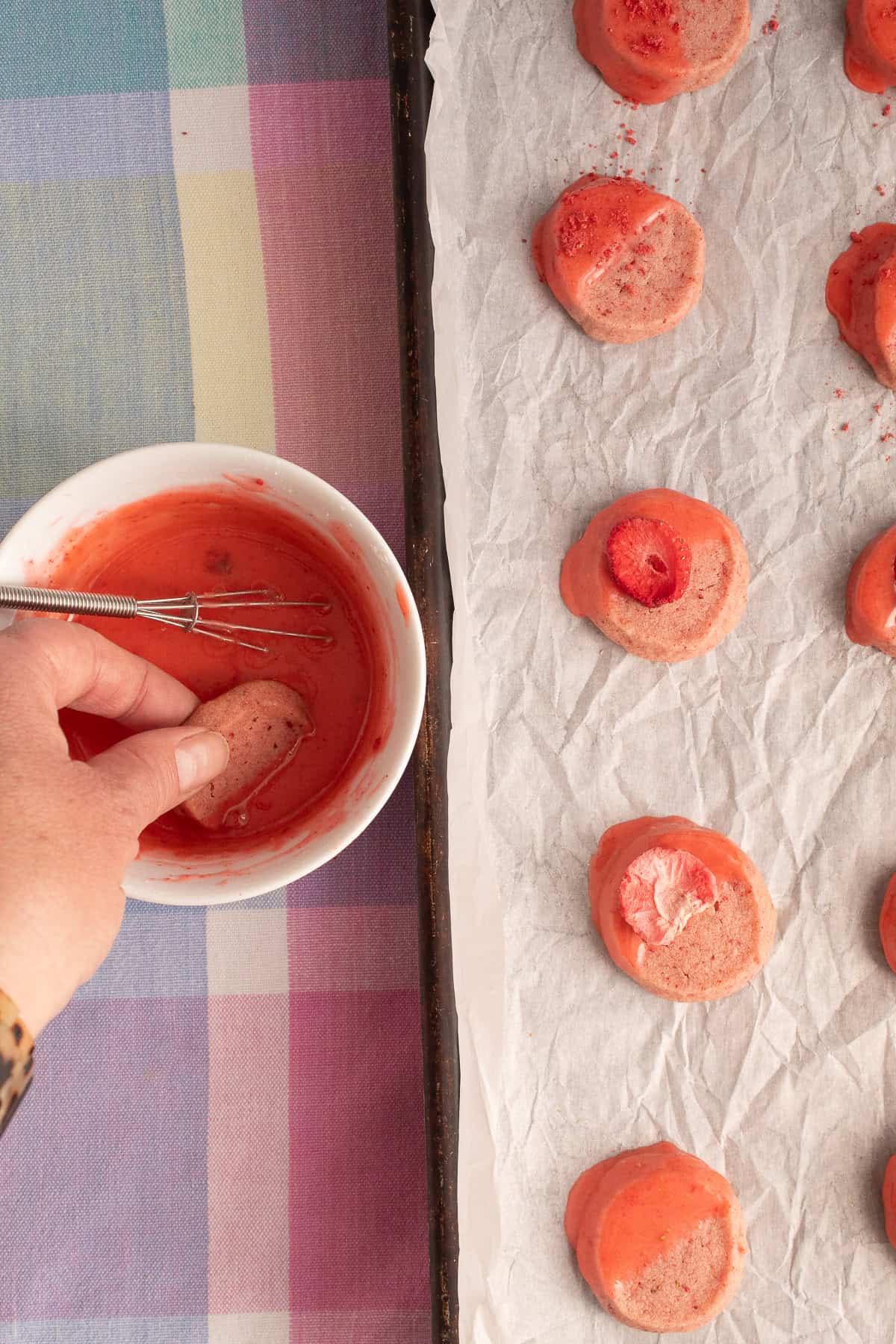 Cookies are dipped in the glaze before drying on a parchment-lined pan.