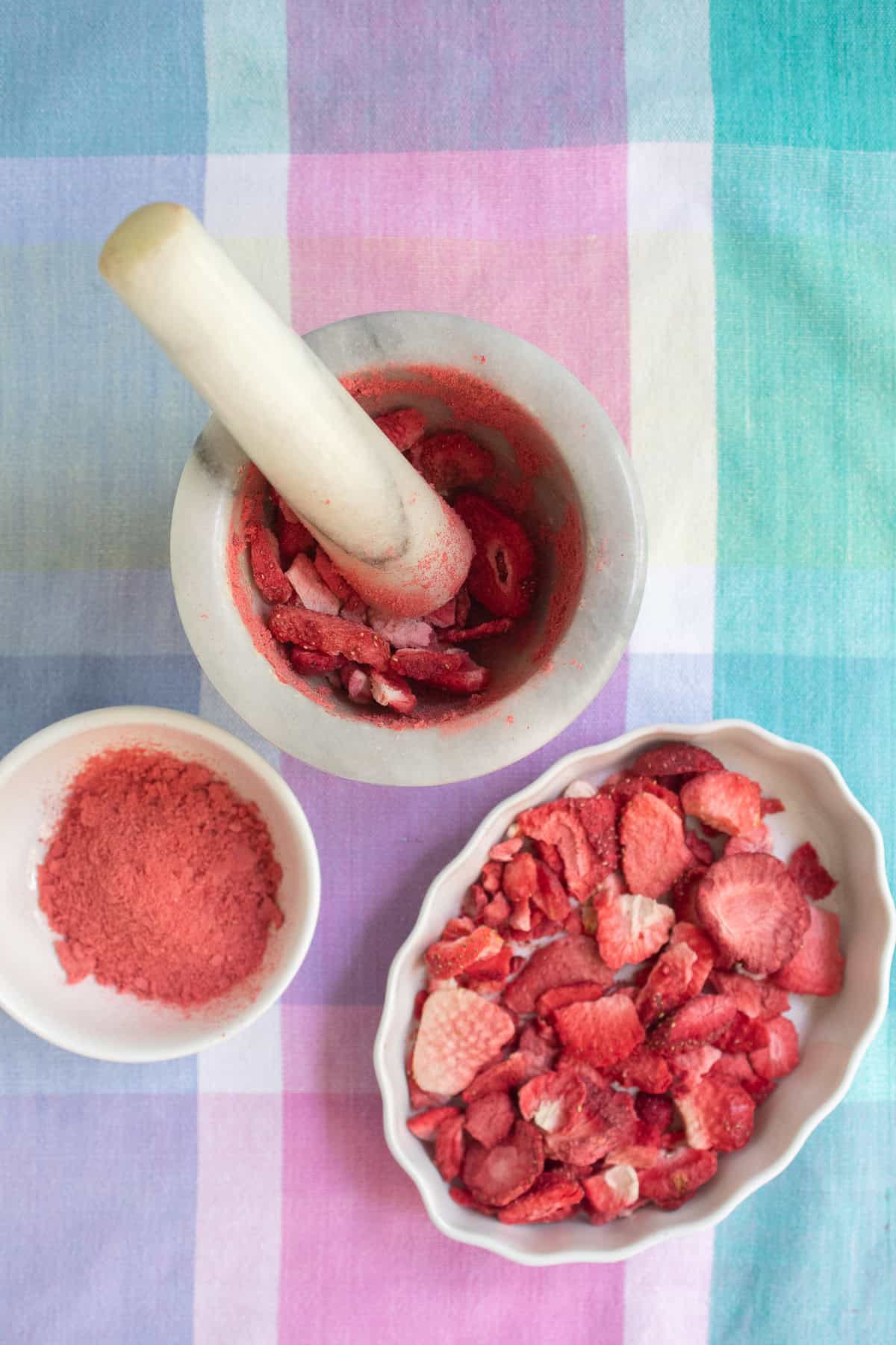 Freeze dried strawberries are crushed into a fine powder with a mortar and pestle.