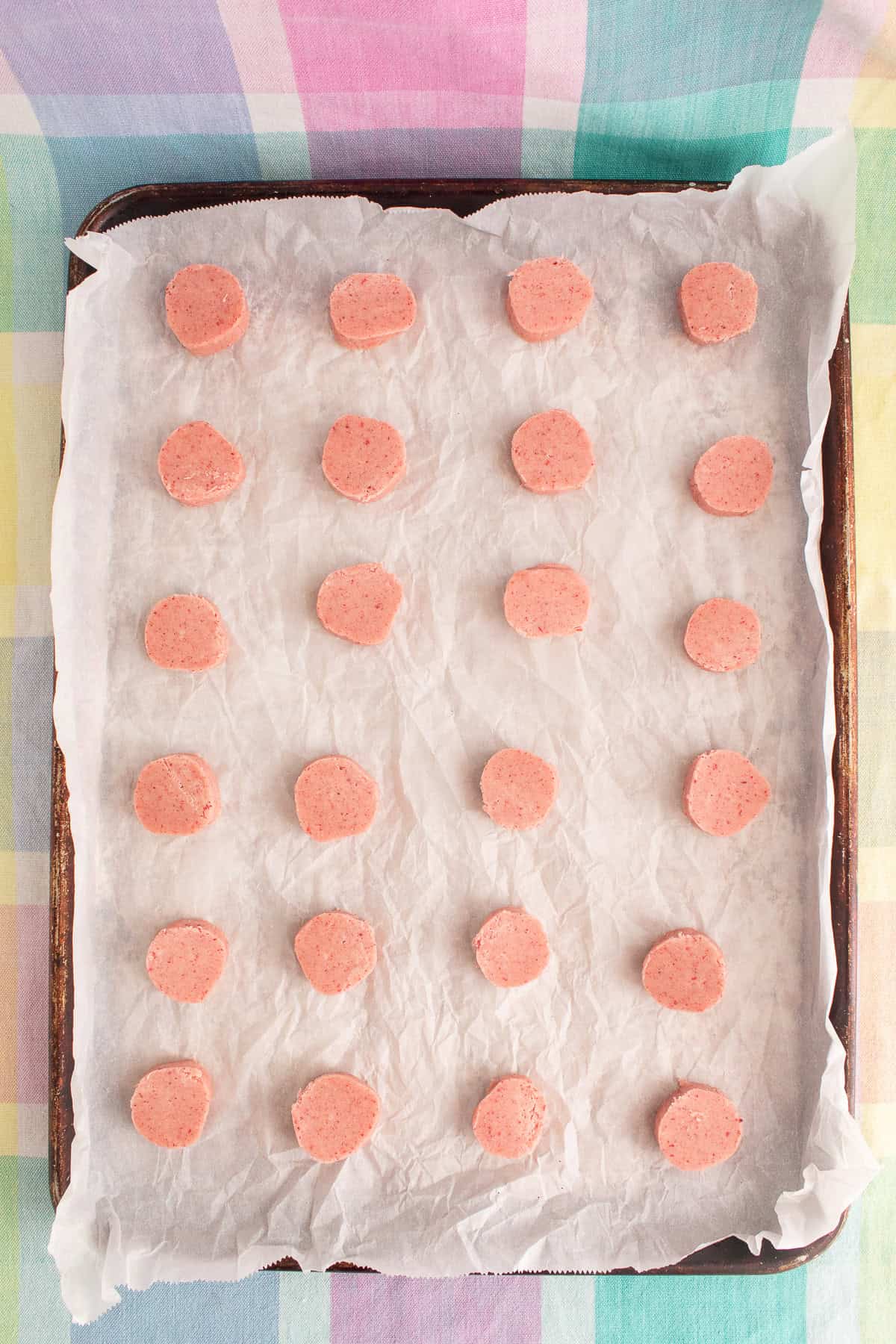 The sliced cookie dough is spaced on a parchment-lined sheet before baking.