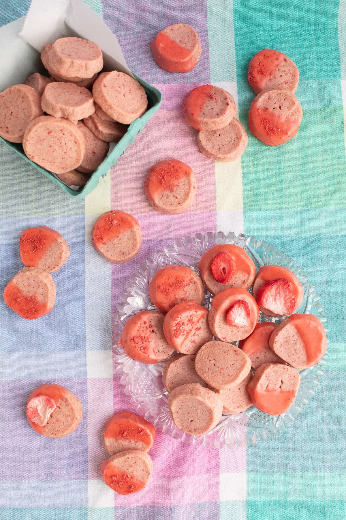 Strawberry shortbread cookies are presented on various serving platters and are decorated with strawberry glaze, dried strawberries, or left plain.