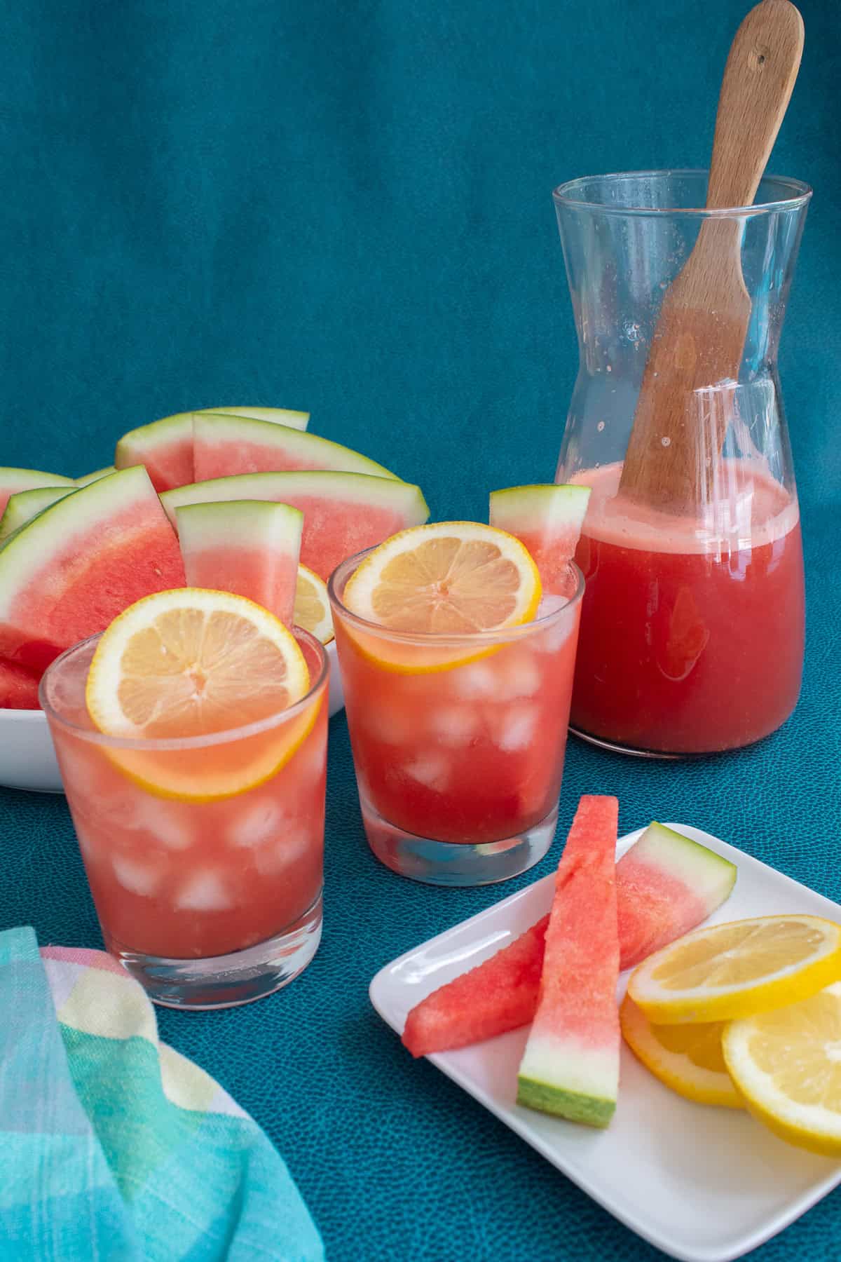 Two glasses of lemonade are garnished with lemon slices.