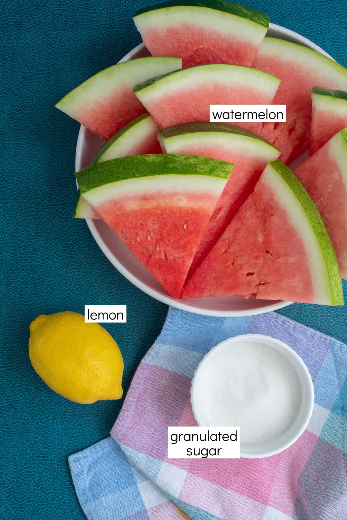 Ingredients for the recipe are displayed and labeled with white text boxes including the words watermelon, lemon, and granulated sugar.