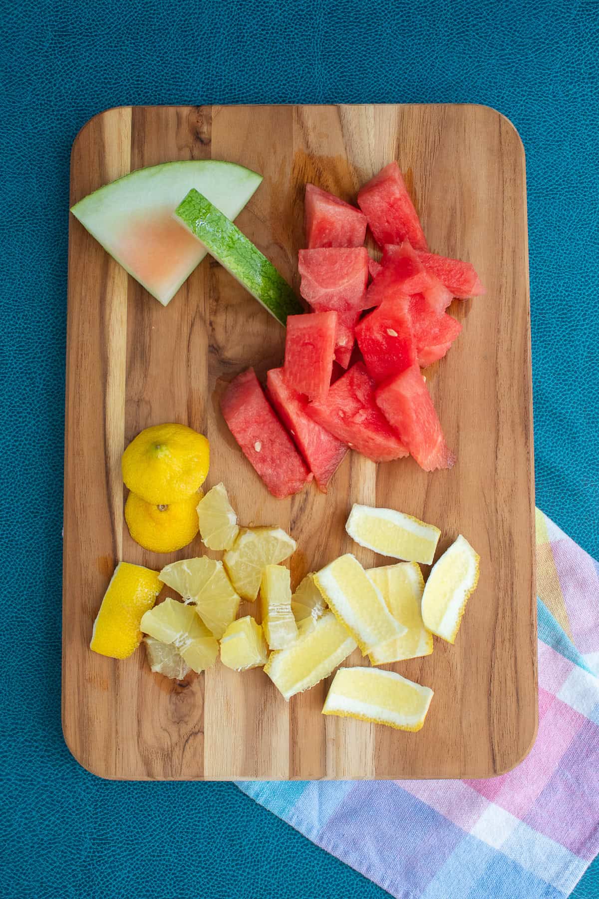 Peeled whole lemon is cut into chunks on a wooden cutting board.