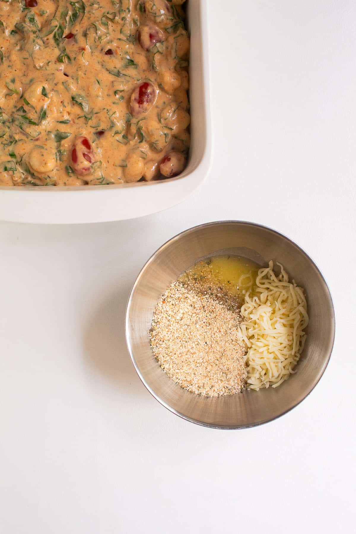 Breadcrumbs, shredded mozzarella, and melted butter are added to a medium stainless steel bowl.