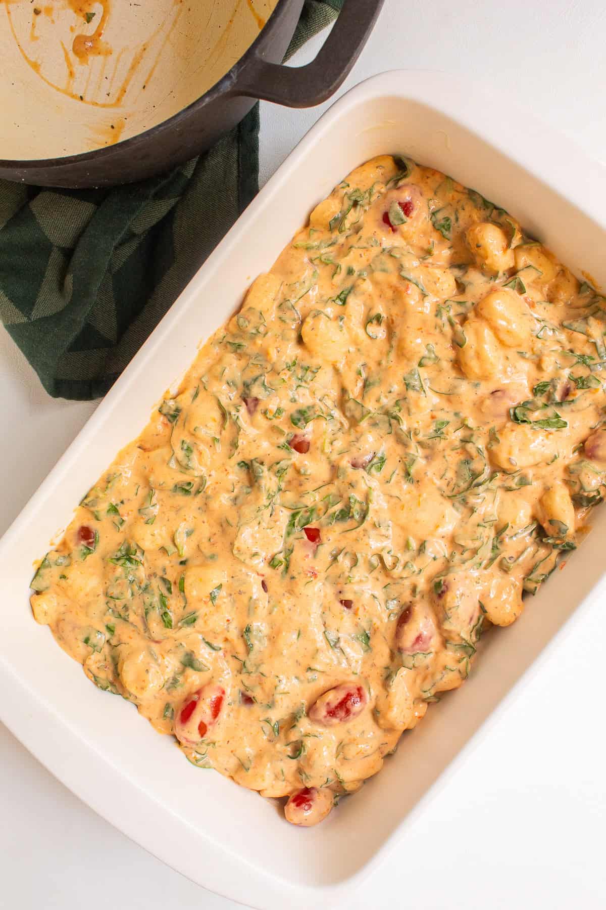 The sauce loaded with gnocchi, spinach, basil, and tomatoes is moved to the prepared casserole dish.