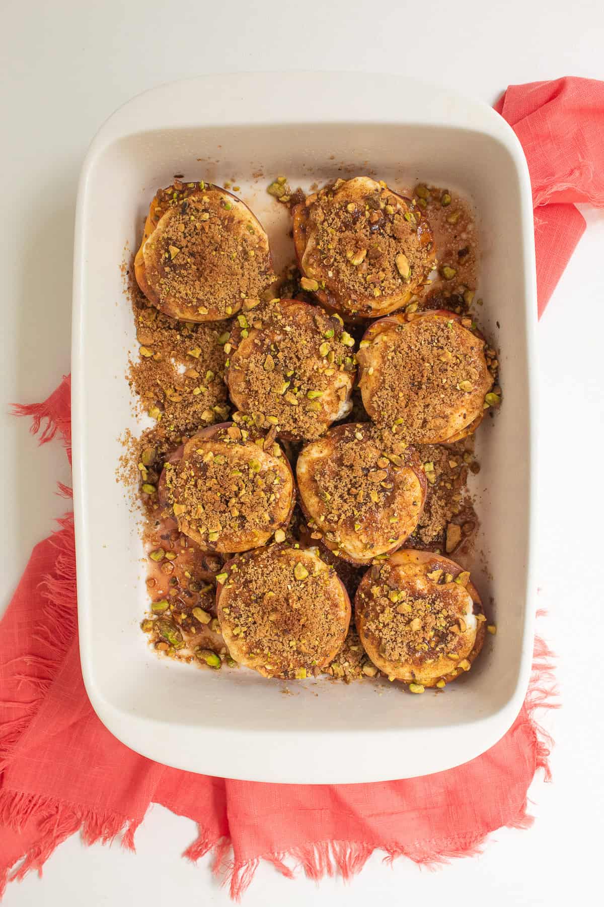 The baked peaches are golden in color and some of the juices have pooled in the bottom of the baking dish.