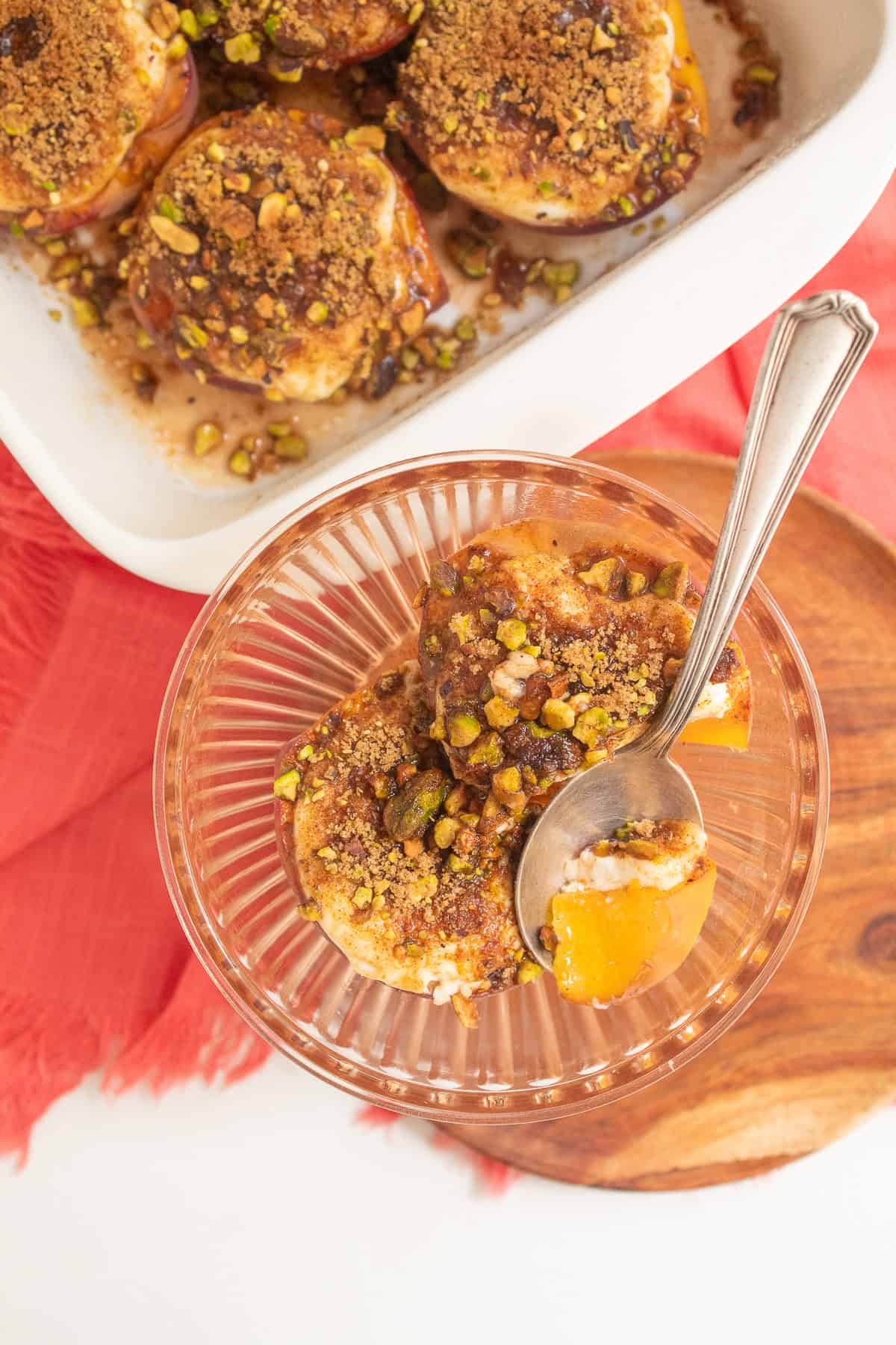 A spoonful of bright yellow peach with sour cream and a toasted pistachio mixture sits in a pale orange bowl.
