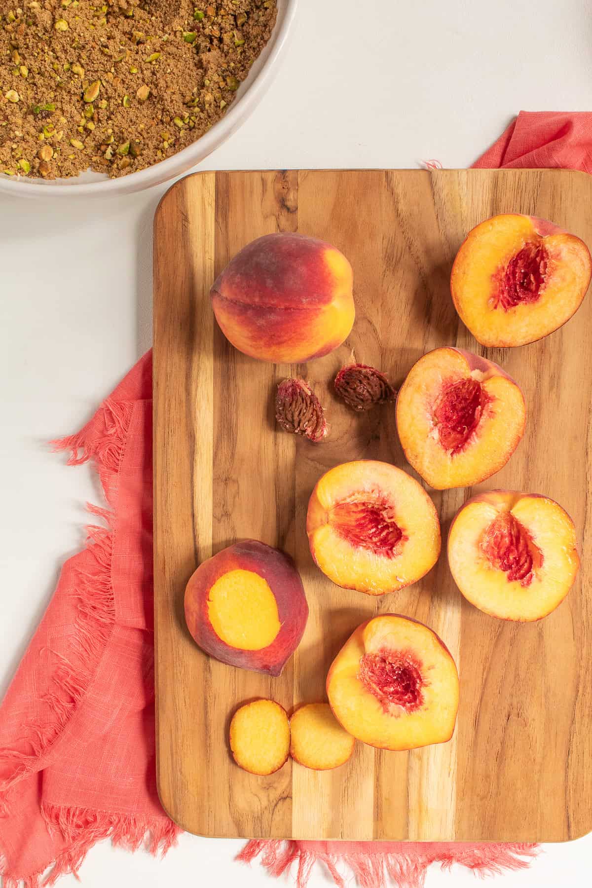 Peaches are halved and small slices are cut off of the rounded edges so that they sit flat in a pan.