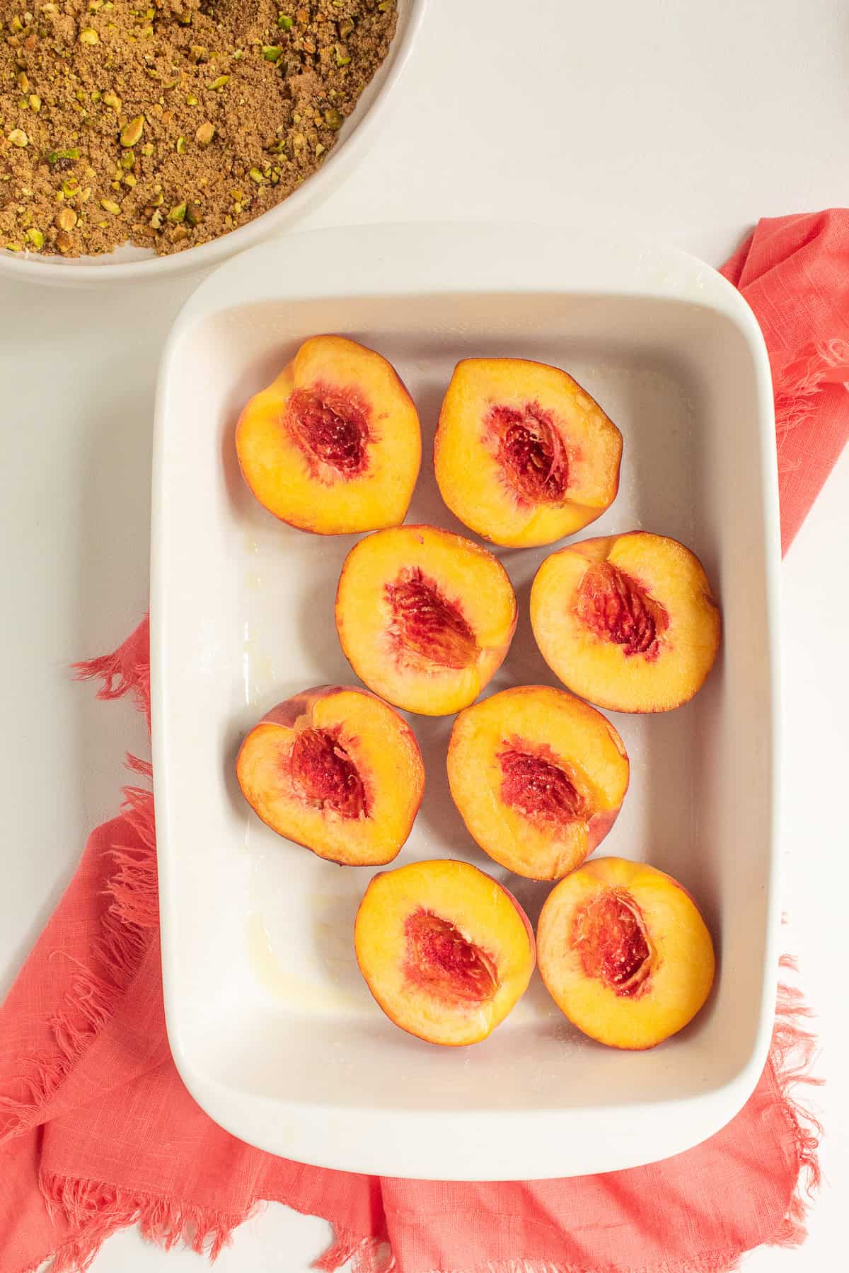 Peach halves are arranged in a white casserole dish.