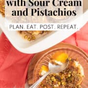 Bright yellow peach is topped with a layer of sour cream and toasted pistachio and brown sugar mixture in a fluted bowl next to a white baking dish. A white text box at the bottom of the image contains the words, "baked peaches with sour cream and pistachios" and "plan. eat. post. repeat."