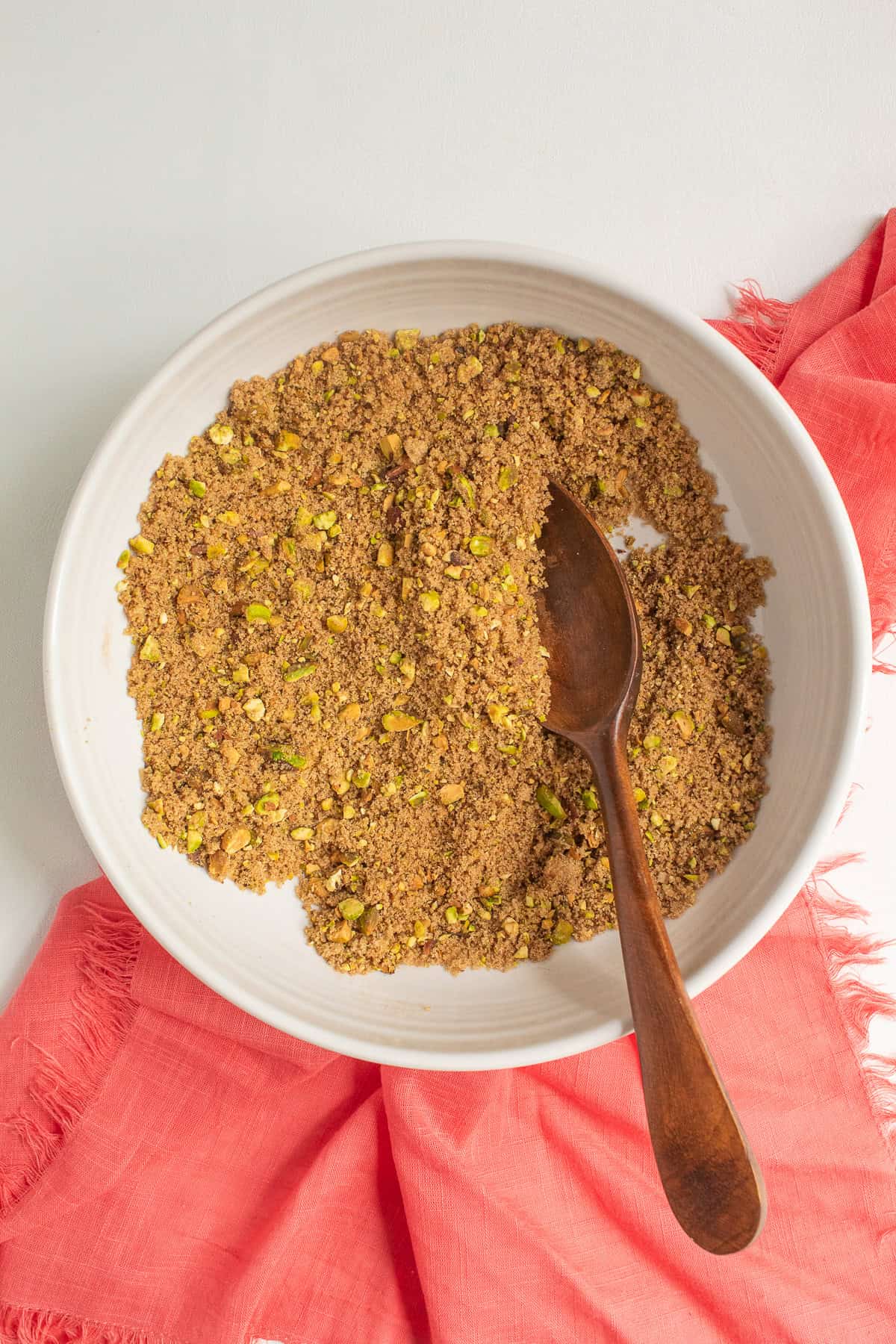 The sandy mixture of crushed pistachios, brown sugar, and cinnamon in a white bowl.
