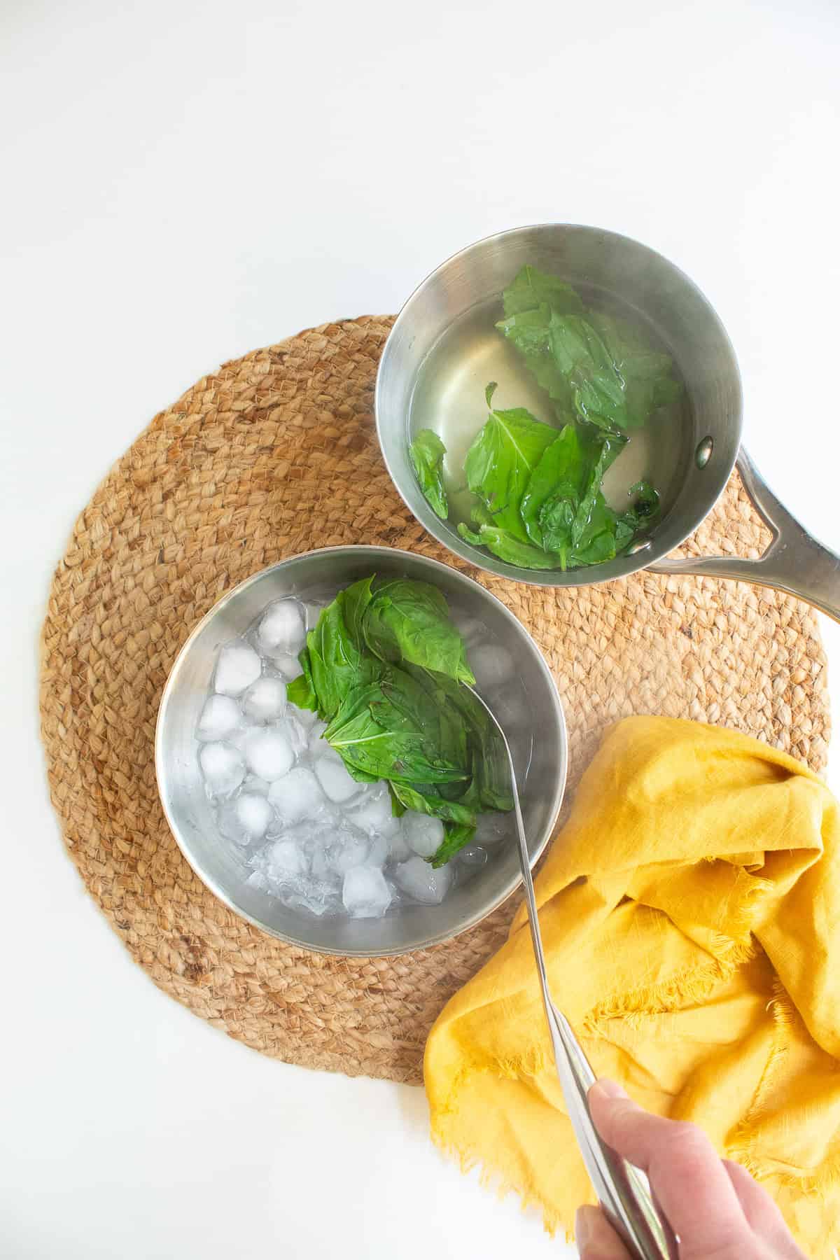 The blanched basil leaves are transferred to an ice bath to cool.
