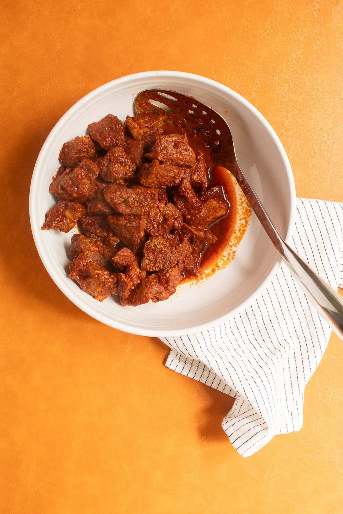 The pork is removed from the cooking liquid using a slotted spoon.