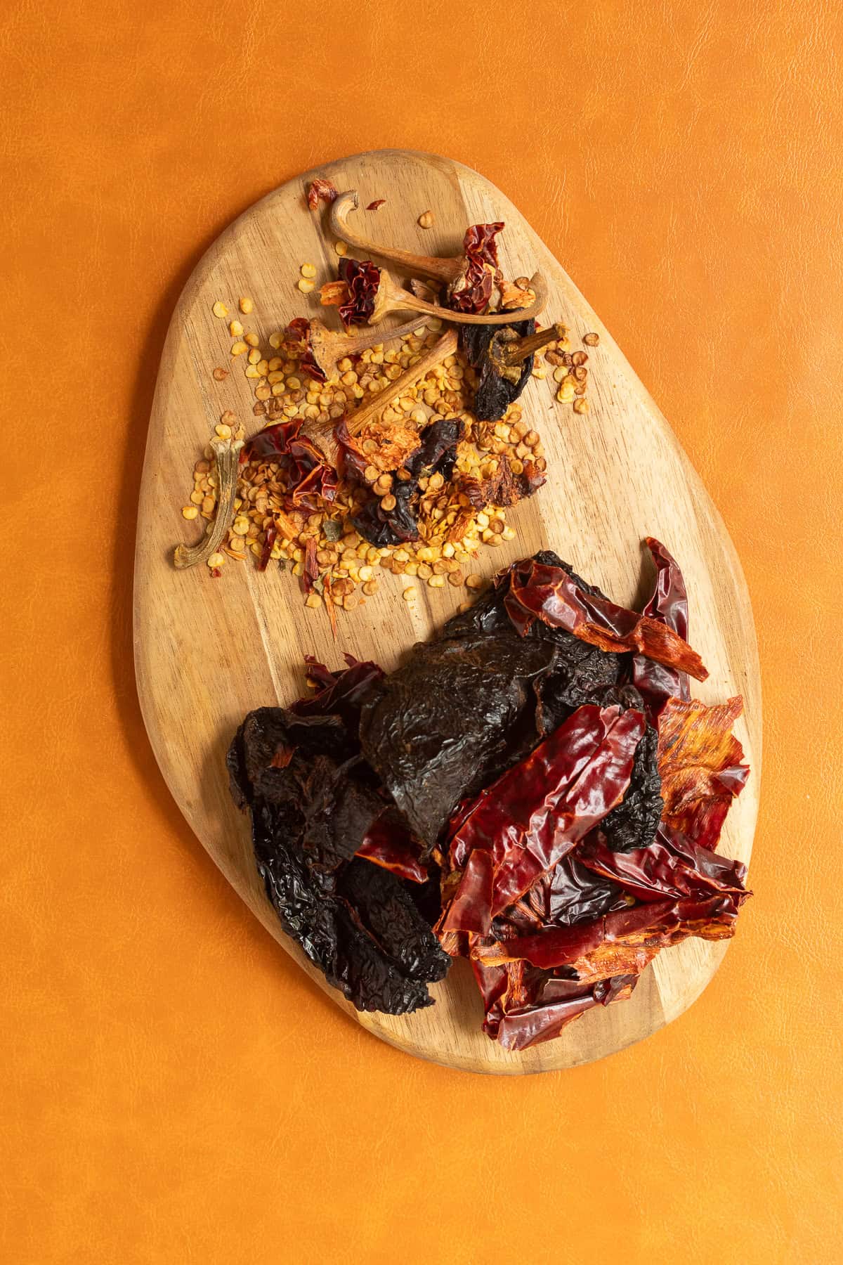 The stems and seeds are separated form the dried chiles on a small wooden cutting board.