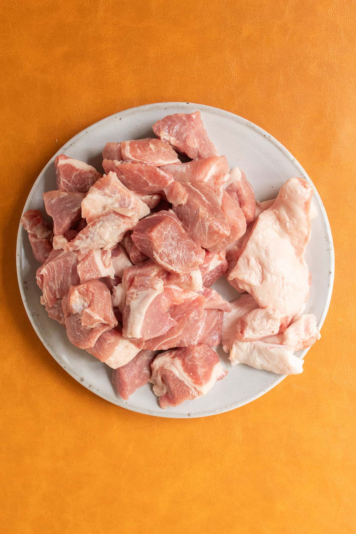 Fat has been trimmed away from pieces of pork that sit on a gray plate.