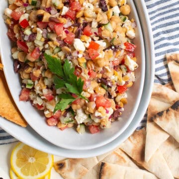 A detail image of the Greek salad dip reveals pieces of cucumber, tomato, feta, olives, red onion, and garbanzo beans