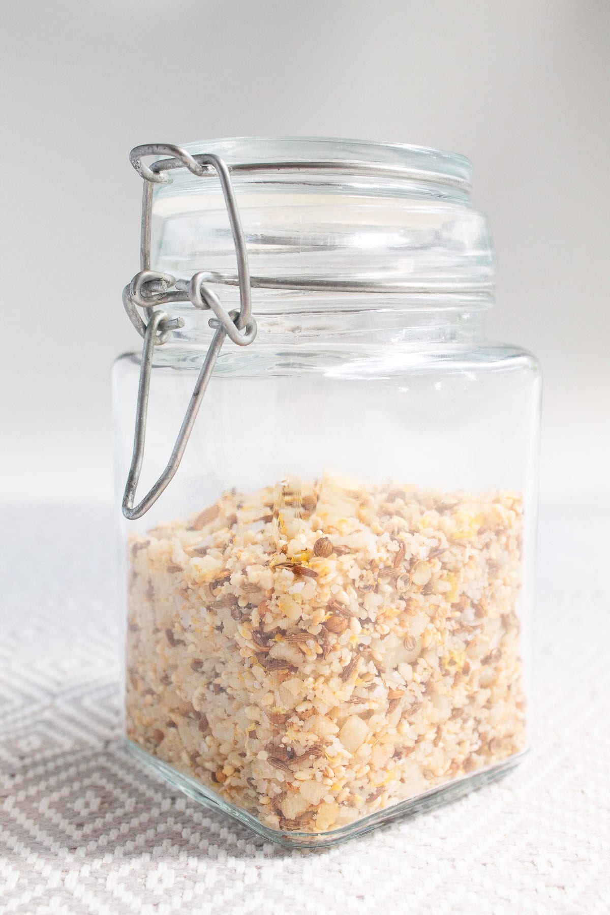 The dukkah is stored in a glass jar with whole and crushed seeds and macadamia nuts visible.
