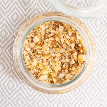 The dukkah is stored in a glass jar with whole and crushed seeds and macadamia nuts visible.