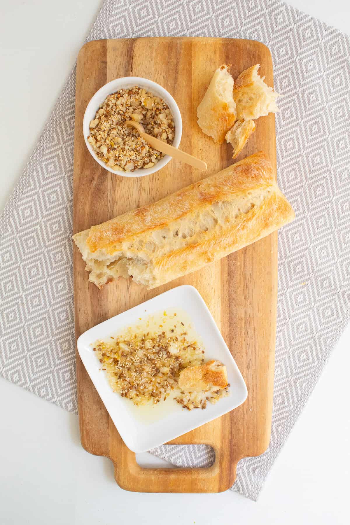Dukkah is served with bread and olive oil on a wooden board.