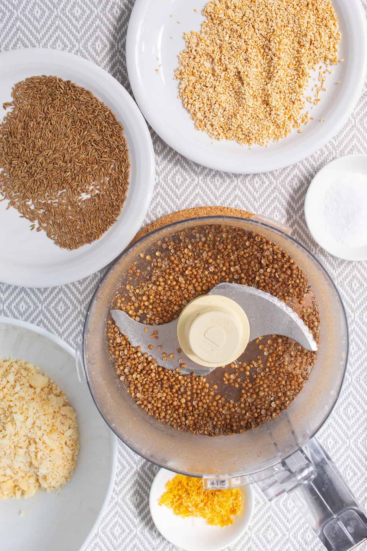 Coriander seeds are processed until they are cracked in half in a food processor.