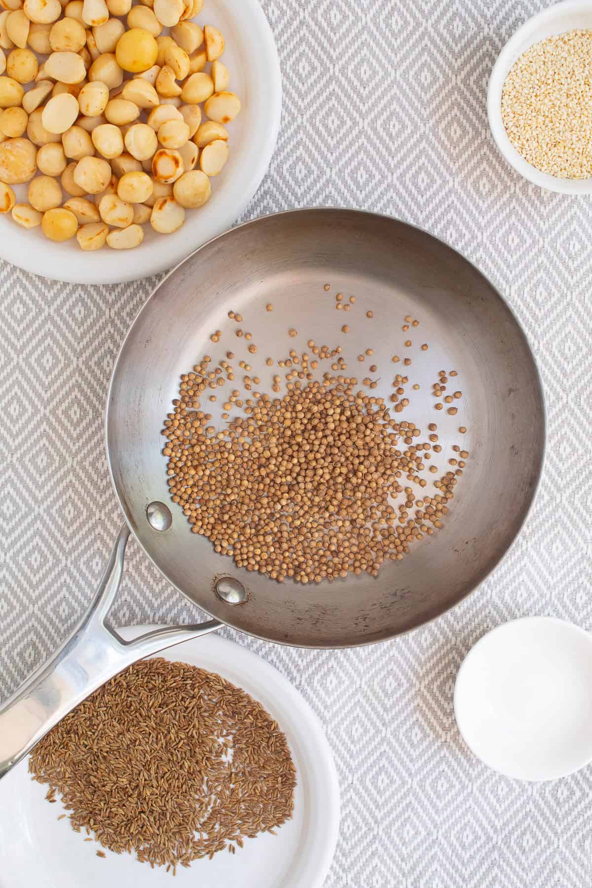 Coriander seeds are toasted in a small stainless skillet.