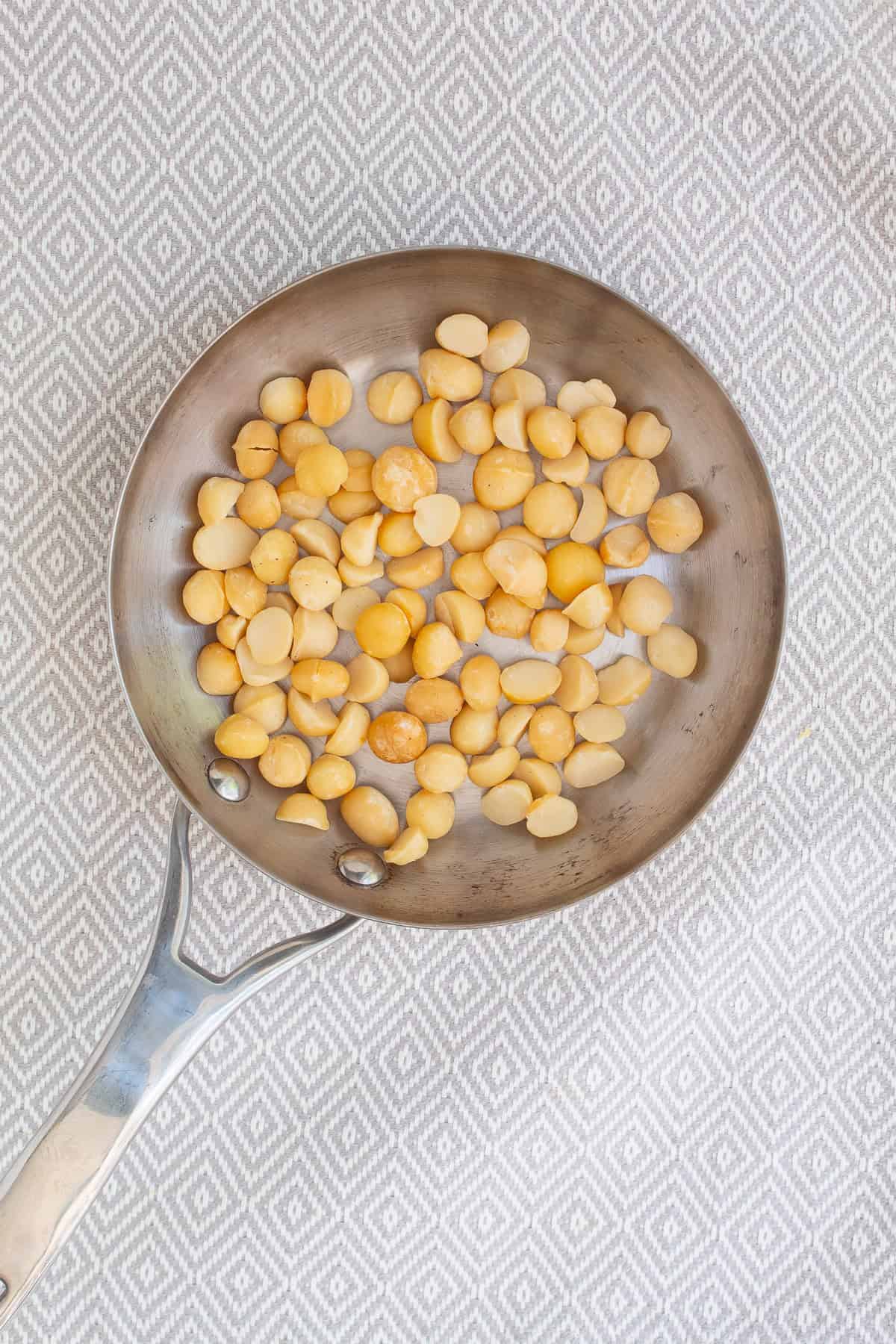 Macadamia nuts are toasted in a small stainless skillet.