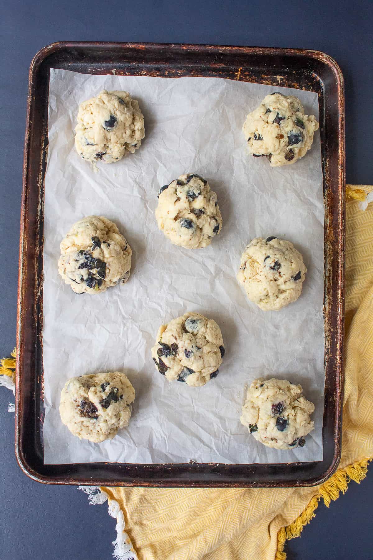 Eight mounds of biscuit dough are spaced out on a sheet pan.