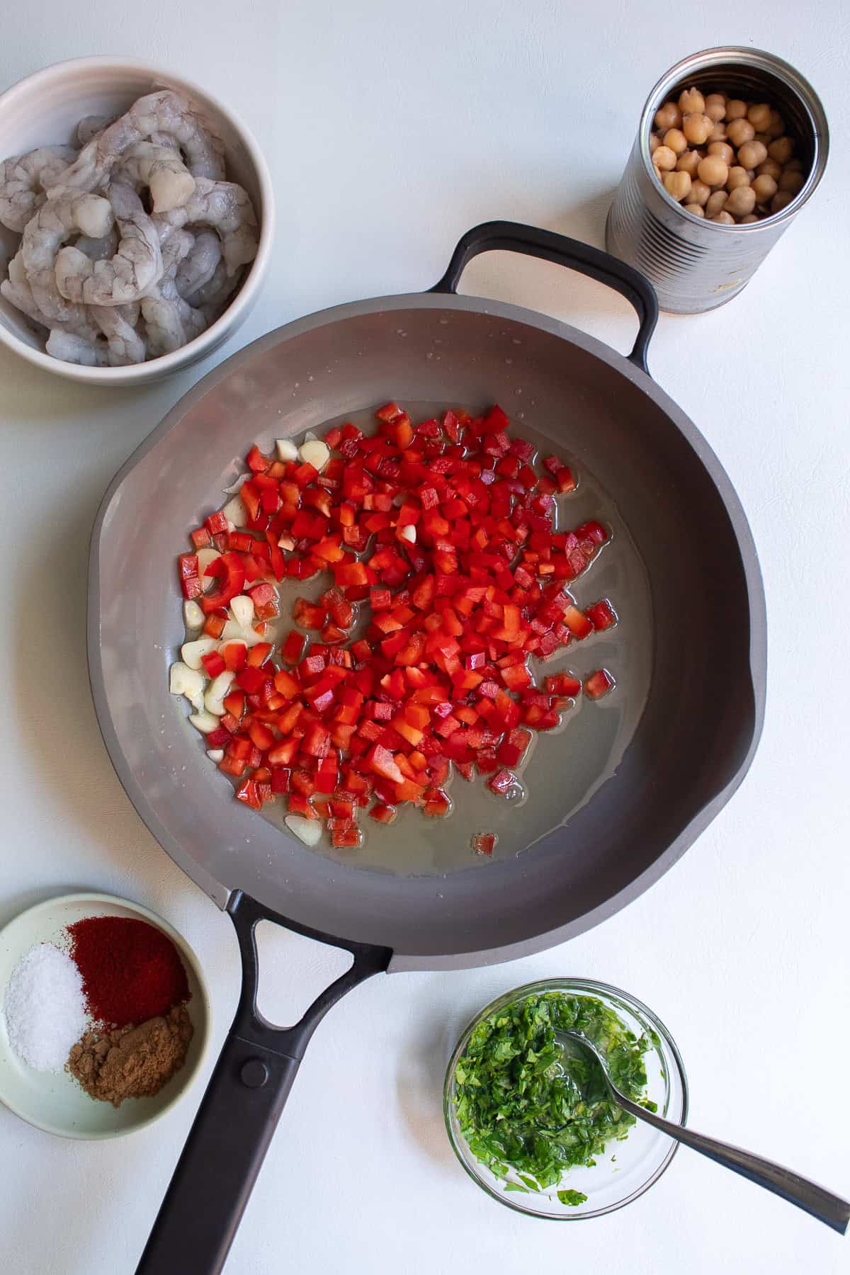 Diced bell peppers are added to the oil along with the sliced garlic.