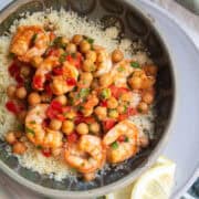 Lemon garlic shrimp are served over a bed of couscous in a green bowl.