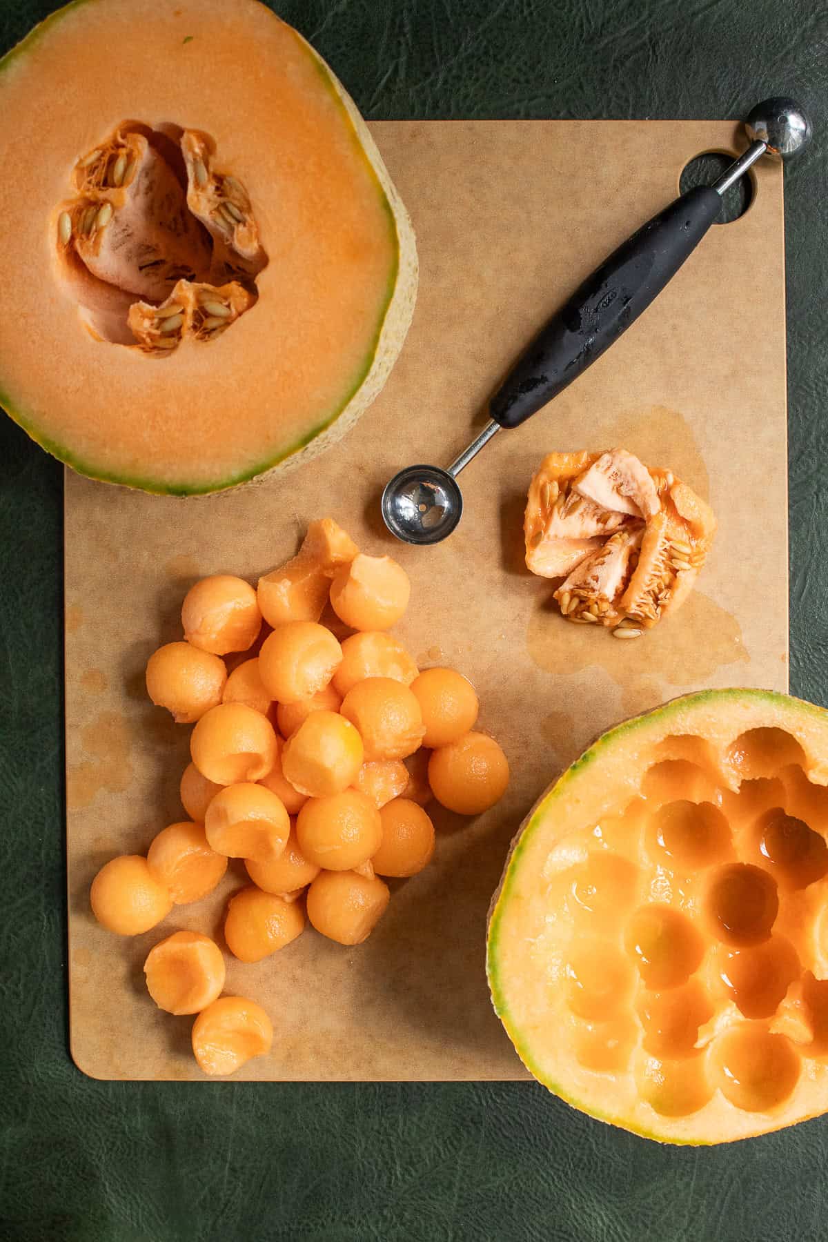 A melon baller is used to cut melon balls from a ripe cantaloupe.