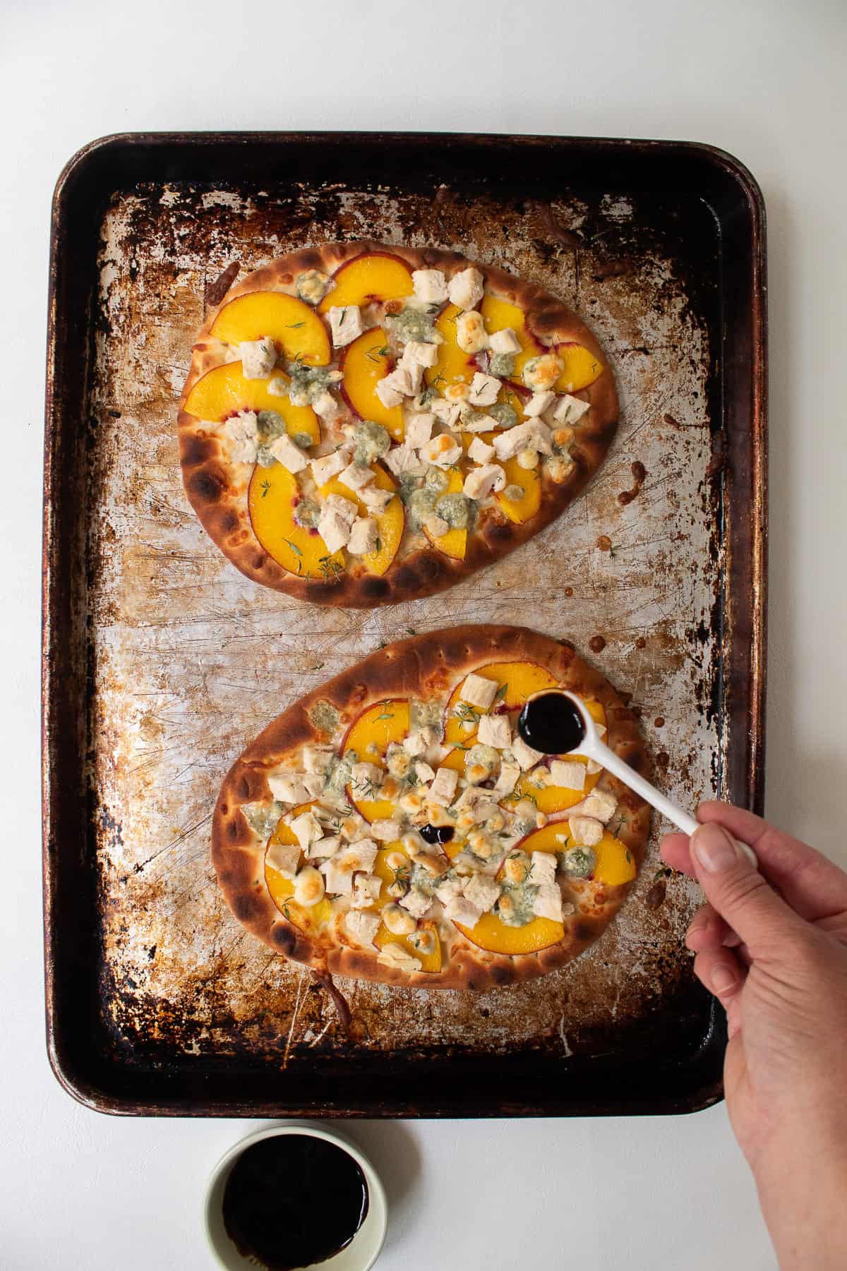 Balsamic glaze is spooned over the baked pizza.