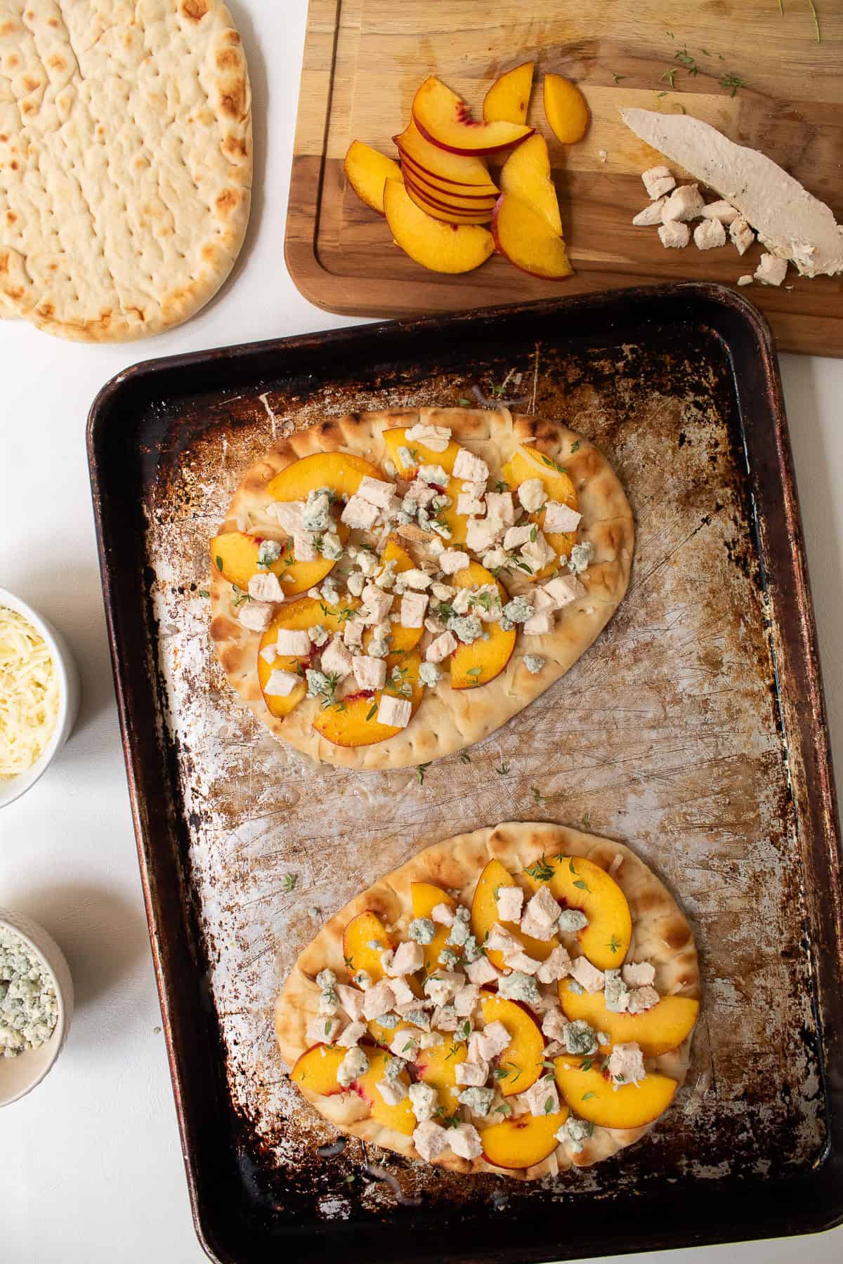 Blue cheese crumbles and thyme leaves are added to the pizzas.
