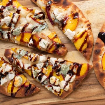 Nectarine pizza with blue cheese, chicken, thyme leaves, and balsamic glaze in detail.