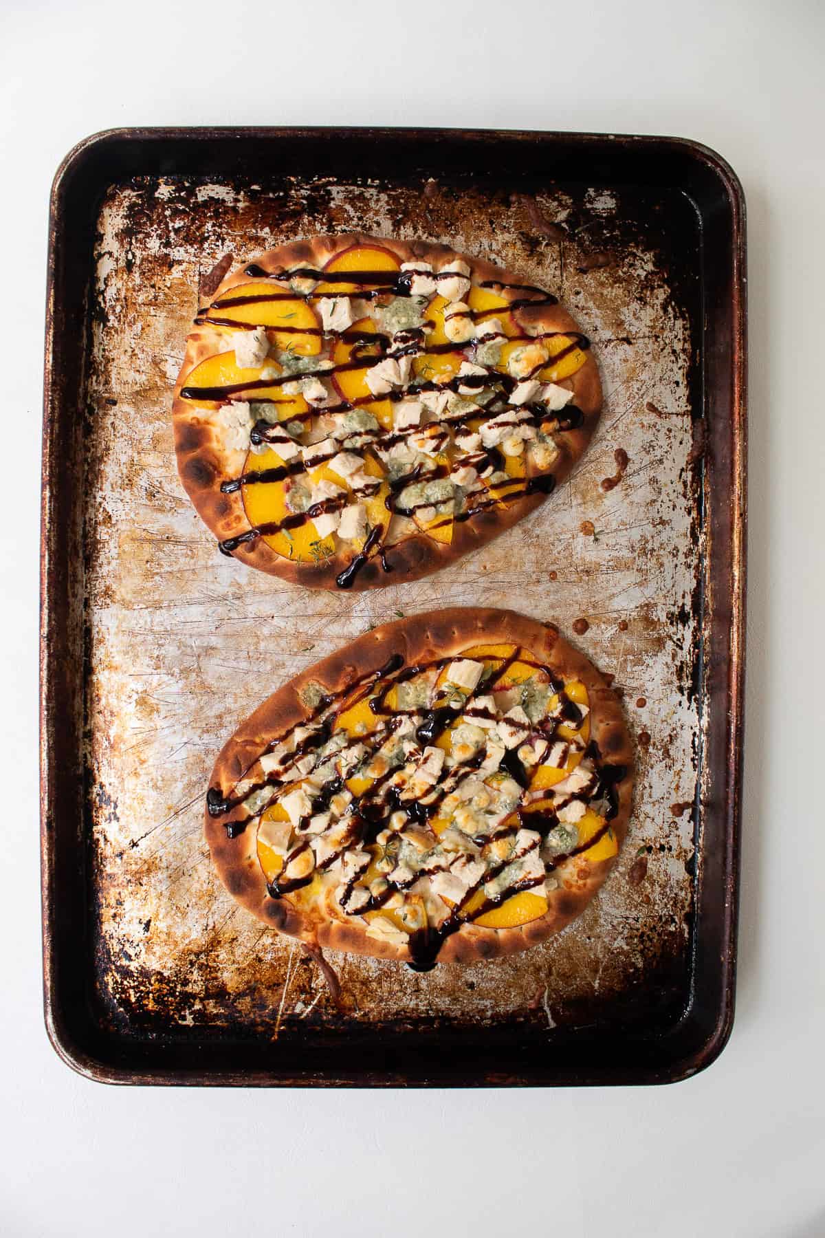 The finished pizzas have a generous drizzle of balsamic glaze.