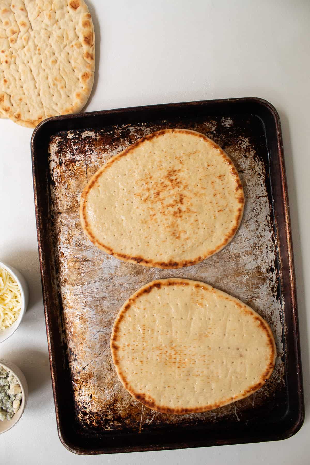 The bottom of the flatbreads is oiled in preparation for broiling.