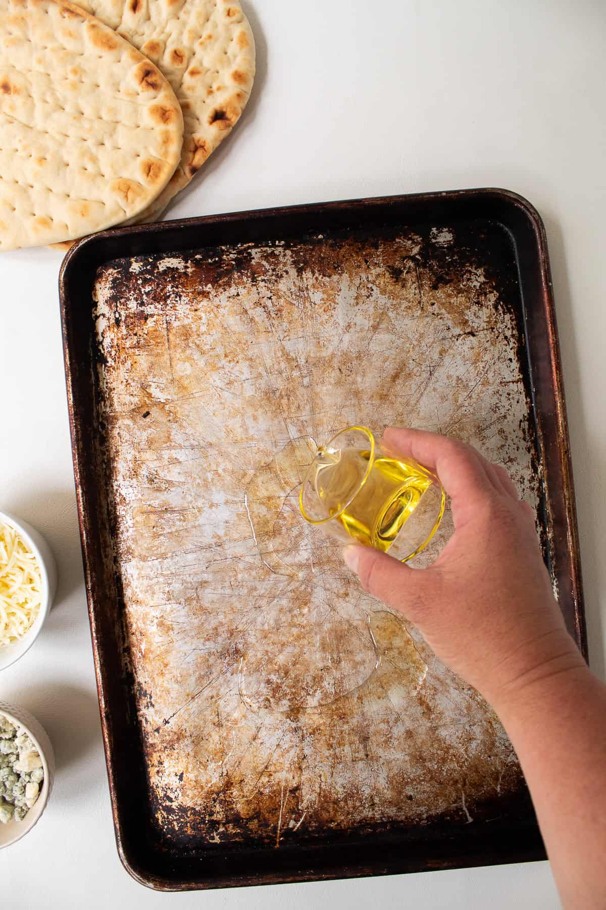 Olive oil is streamed onto a sheet pan.